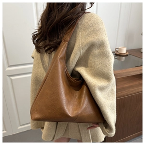 Brown leather tote bag worn as a shoulder bag showing large capacity and minimalist style