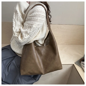 Detail view of large brown hobo bag with natural leather texture worn over a white sweater