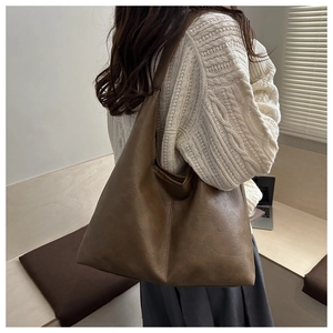 Dark brown large capacity tote bag with leather texture shown in a casual lifestyle setting