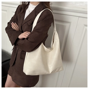 Detail of a large cream hobo bag with glossy ripple texture and slouchy design
