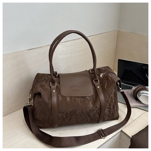 Gros plan du grand sac de voyage marron avec texture plissée et poignée en cuir chic