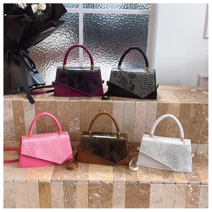 Collection of color-block textured handbags with asymmetrical flaps on stone steps