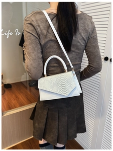 Detail of white crossbody bag featuring snake skin texture flap on a female model