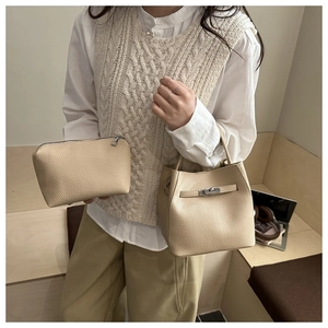 Close-up of beige lychee textured leather bucket bag with silver metal buckle and small pouch