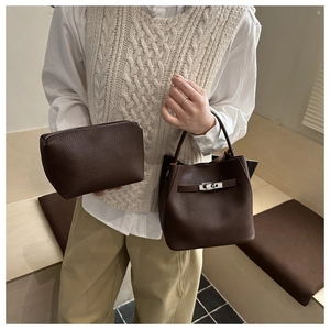 Close-up of deep brown lychee leather bucket bag with matching clutch and metal buckle