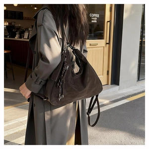 Detail of dark brown suede hobo bag showing large capacity and textured finish on a model
