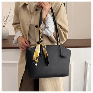 Detail of black matte leather tote bag with elegant floral scarf on the handle