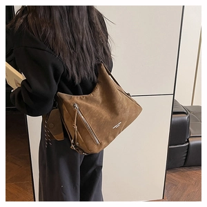 Braune Schultertasche aus strukturiertem Kunstleder mit kleiner Seitentasche am Modell