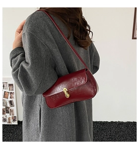 Detailed macro shot of vintage dark red leather bag with gold oval rotating clasp