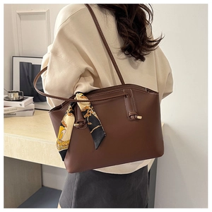 Detail shot of brown faux leather tote bag with decorative scarf worn over the shoulder