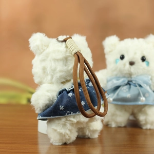 Close-up of white plush bear keychain with floral dress showing soft fur texture