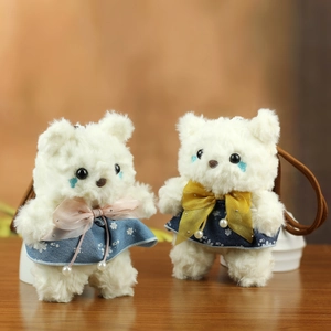 Detail of two white teddy bear plush charms with floral dresses and pearl accents