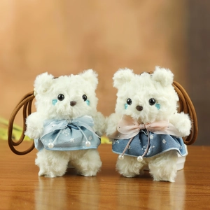 Detail of two cute teddy bear plush pendants in blue floral dresses on wood surface