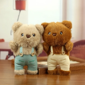 Plush teddy bear keychains in mint green and beige overalls with soft faux fur texture