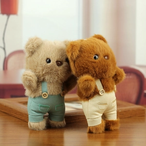 Detailed view of plush teddy bear keychains with overalls and wooden button accents
