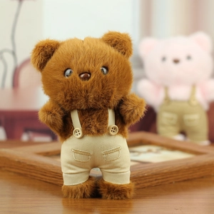 Close-up of a brown plush teddy bear wearing miniature beige overalls with button details