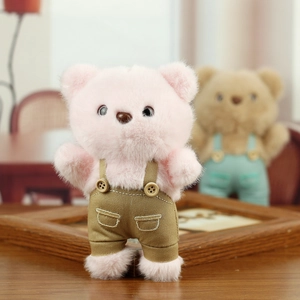 Detail of pink plush bear keychain wearing brown suspender pants with wooden buttons