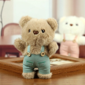 Close-up of plush teddy bear wearing green overalls with fine wooden button details