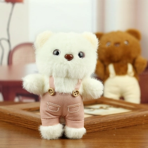 Close-up of white plush teddy bear in pink striped overalls on a wooden table