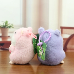 Rear view of pink and purple plush hamster keychains with plastic hooks on wooden desk