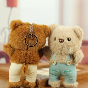 Detail of plush bear pendants in beige and brown with cute blue overalls and keyrings
