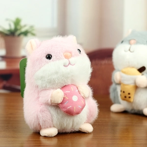 Close-up of a pink plush hamster holding a donut charm with soft furry texture