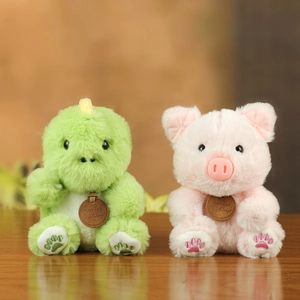 Close-up of soft plush green dinosaur and pink pig toys with detailed paw embroidery