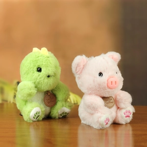 Close-up of soft plush dinosaur and pig dolls with wooden logo tags on wood table