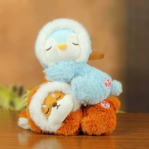 Close-up of sleeping plush penguin and fox dolls with soft hoodies and interactive buttons