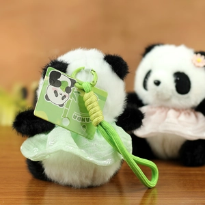 Dettaglio di un portachiavi panda di peluche con vestito floreale verde e laccetto intrecciato
