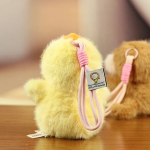 Close-up of yellow plush animal keychain with soft long fur and pink braided lanyard
