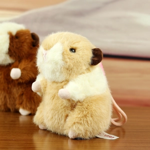 Close-up of soft plush hamster keychain with brand label and fluffy texture on wooden table