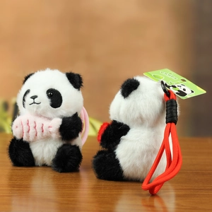 Dettaglio di portachiavi panda in peluche con pelliccia soffice e pesce rosa