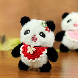Detail eines Pandaplüsch-Anhängers mit rotem Häkellatz und kleiner Blumendekoration
