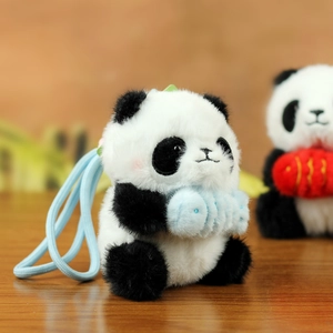 Dettaglio ravvicinato di un portachiavi panda in peluche con pesce blu e cinturino intrecciato