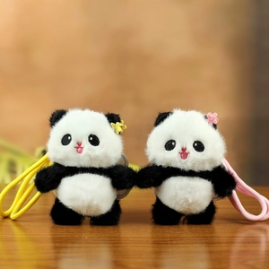 Cute panda plush keychain pair with flower clips and ropes on a wooden surface