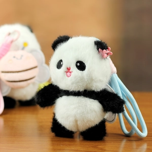 Close-up of plush panda keychain with pink flower hairclip and heart-shaped embroidery