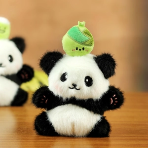Close-up of cute panda plush keychain with green zongzi hat and pink embroidered paw pads