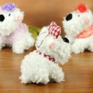 Close-up of fluffy white plush dog charms with colorful bow and flower decorations