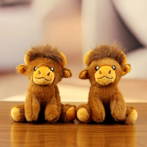 Two cute plush Highland cattle keychains with brown long hair on a wooden table
