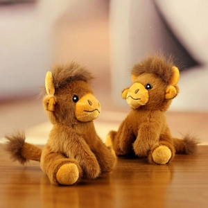 Close-up of two cute brown plush cow keychains with soft fur texture on a wooden table