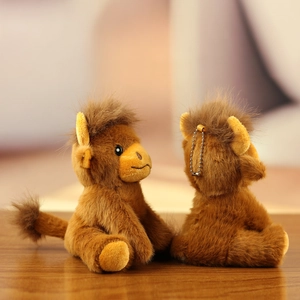 Detail of cute brown plush monkey charms with metal bead chains on a rustic wooden desk