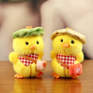 Pair of cute yellow plush ducklings with hats and scarves standing on a wooden table