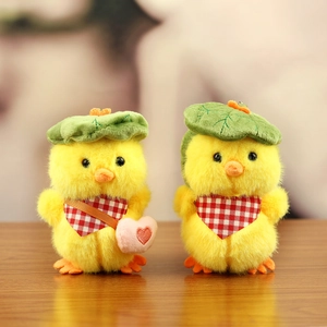 Detail of two plush yellow ducklings with green leaf hats and red plaid scarves
