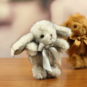 Close-up of a plush rabbit doll with grey mottled faux fur and a silver satin bow tie