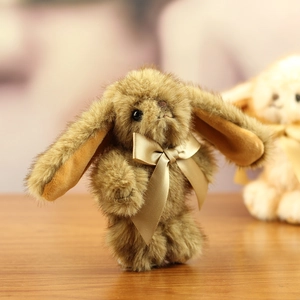 Detailed close-up of fluffy brown plush rabbit with a glossy champagne gold satin bow