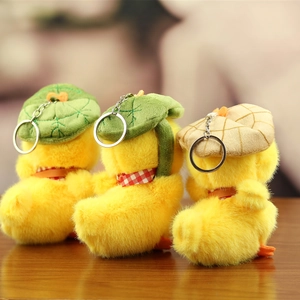 Rear view of three plush duck keychains with different hats on a wooden table