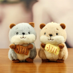 Cute plush hamster keychains in blue and beige colors holding small fish toys on wood