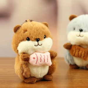 Close-up of soft plush hamster keychain with fish accessory on wooden table