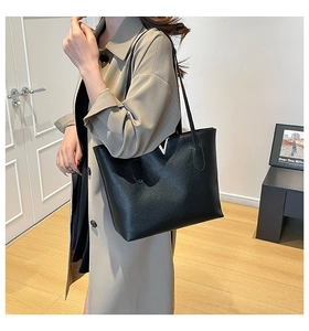 Close-up of black lychee grain leather tote bag with gold V logo on khaki trench coat